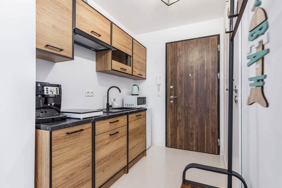 A compact kitchenette with wood-toned cabinets, a microwave, stovetop, and coffee maker.