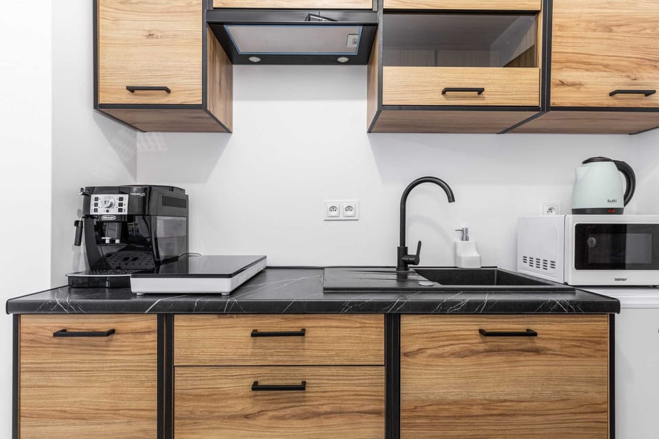 A compact kitchen area featuring wooden cabinets, a microwave, stove, and coffee maker. Functional and modern, with ample storage.