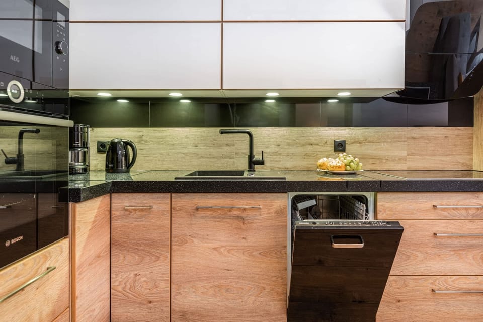 Another angle of the kitchen, showing a microwave and coffee maker integrated into the cabinetry. The black and wood design gives it a sophisticated look.