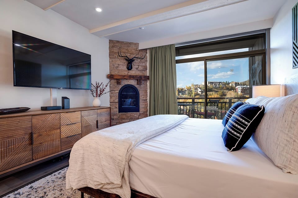 Unwind in your plush bedroom with a cozy fireplace, flat-screen TV, and stunning views through the private balcony—perfect for peaceful mornings and relaxing evenings.