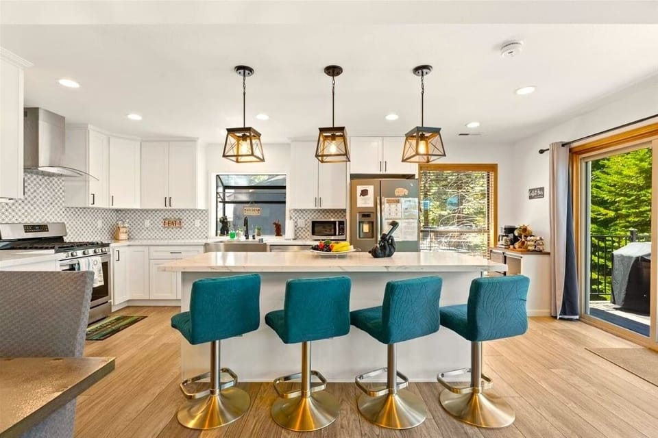 The spacious kitchen island with teal velvet barstools is perfect for morning coffee, snacks, cocktails, or chatting while meals are prepared.