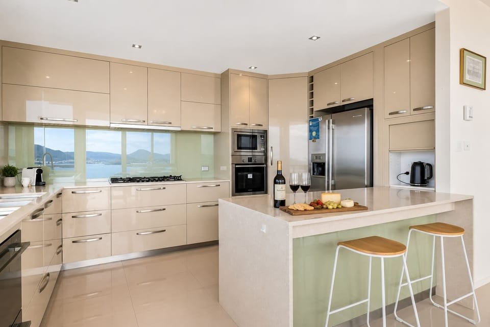 Modern, fully equipped kitchen with generous island bench and breakfast seating—perfect for preparing meals or enjoying wine and cheese together.