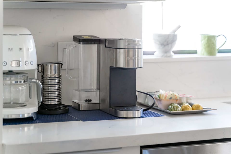A dedicated coffee bar area with a coffee maker, espresso maker, and a milk frother for all your caffeine needs.