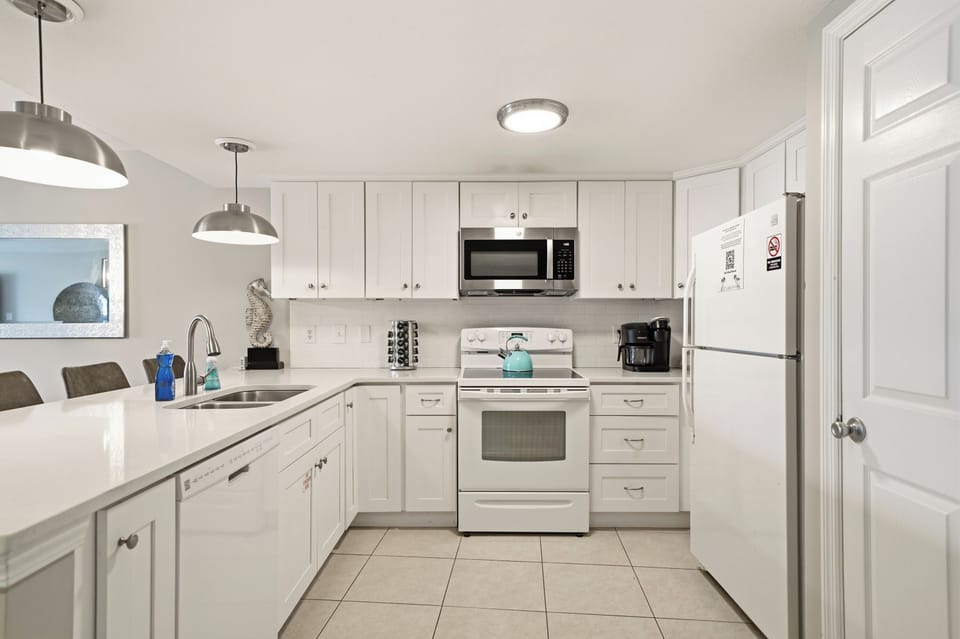 Cook with ease in the fully equipped kitchen featuring bright white cabinetry, ample counter space, and bar seating.