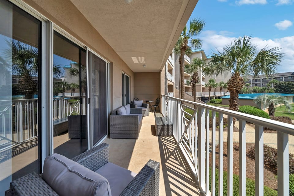 Spacious balcony seating with serene views of swaying palms and the pool area.
