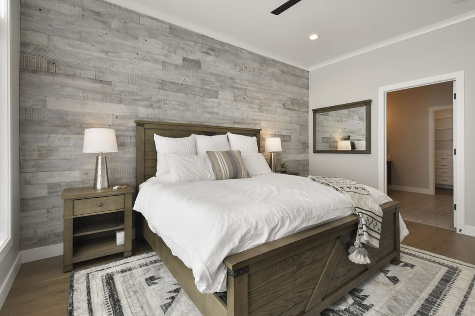 Peaceful primary suite featuring a king bed, rustic wood accent wall, and warm mountain-modern design.