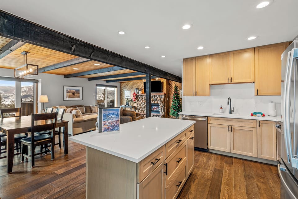 Your spacious kitchen features sleek quartz counters, warm wood cabinets, and stainless appliances, flowing seamlessly into the cozy living area.