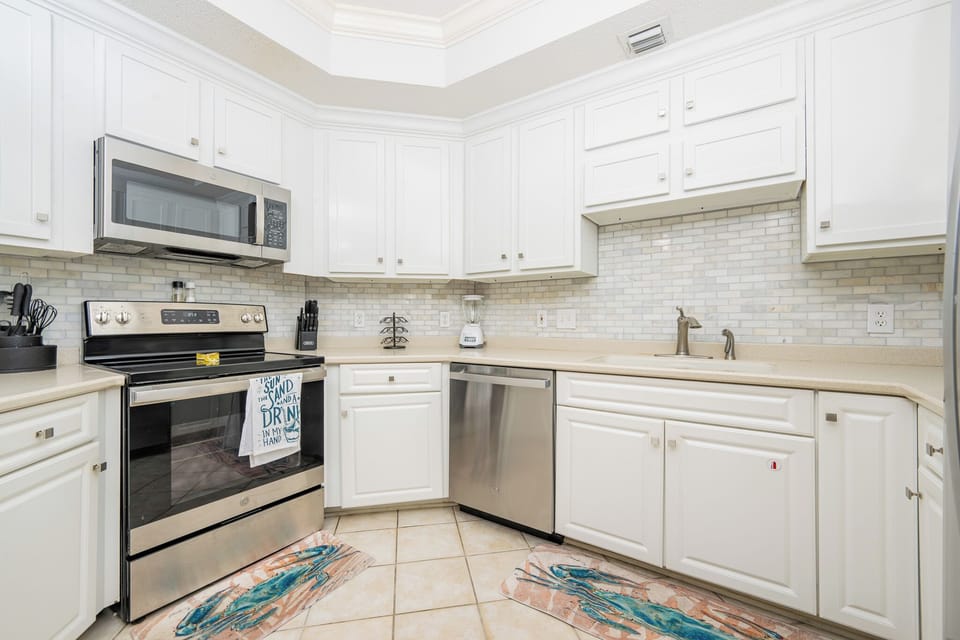 Prepare meals in this kitchen with elegant cabinetry, stainless appliances, and stylish backsplash