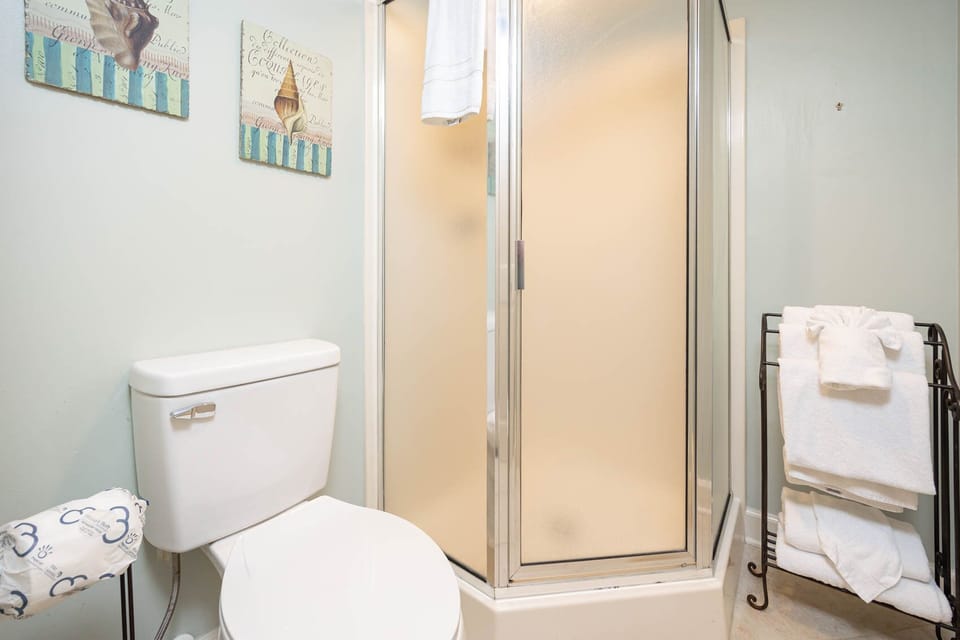 Brightly colored wall art complements the guest bath featuring a walk-in shower and neatly arranged white towels