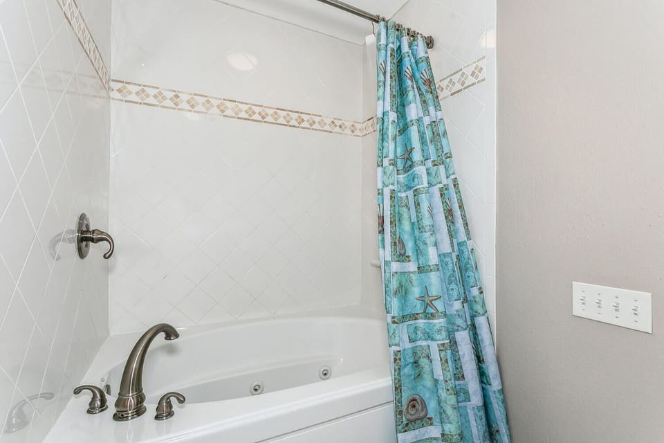 Unwind in your jetted tub with coastal-themed curtains adding a soothing touch of beachy charm.