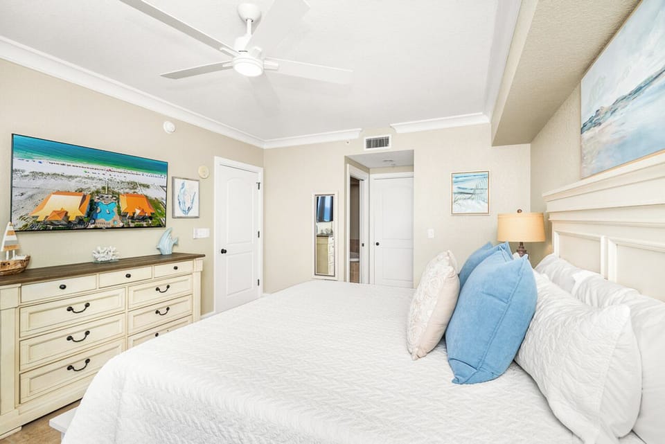 Drift into peaceful sleep in your coastal bedroom with soft linens, beach artwork, and gentle ceiling fan creating the perfect retreat.