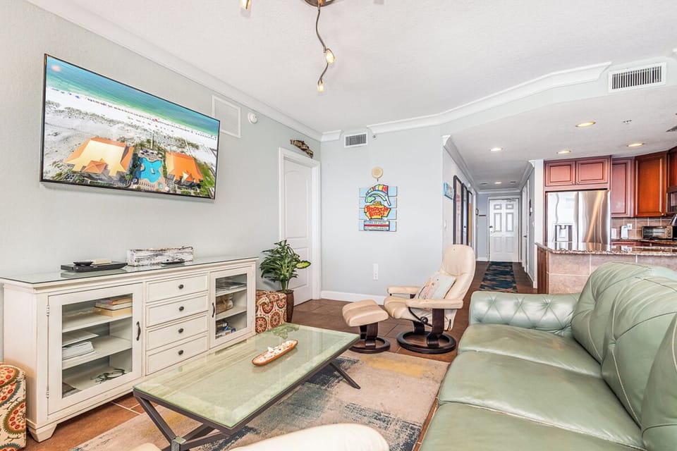 Settle into your bright, inviting living room with plush seating, a large TV, and beach-inspired decor that makes relaxation easy. Your open layout flows seamlessly into the kitchen, giving you space to unwind and feel right at home.