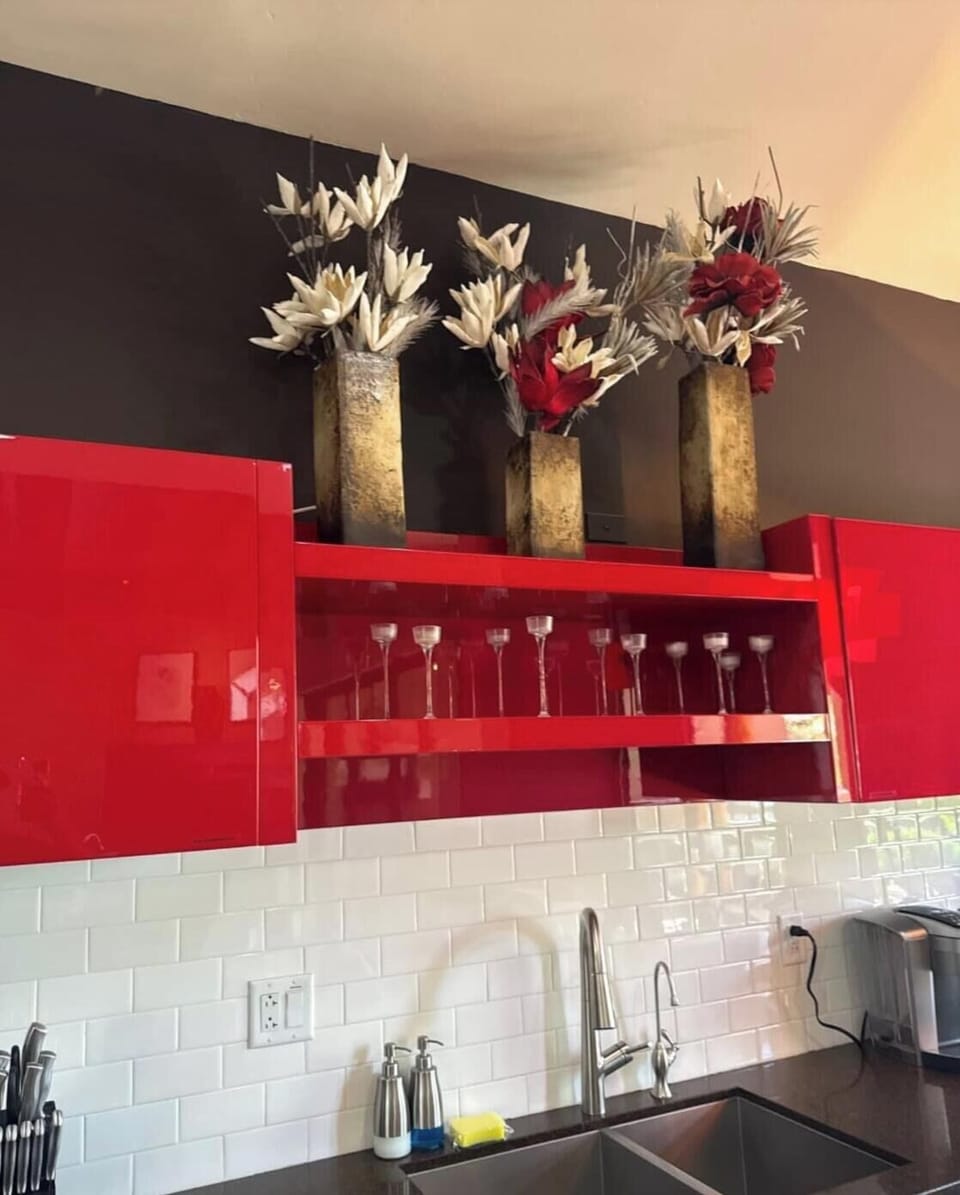 Cook your favorite meals in a stylish kitchen featuring bold red cabinetry, modern appliances, and elegant subway tile backsplash that adds a contemporary touch to your stay.