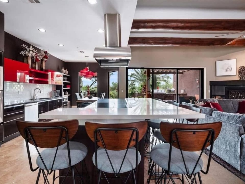 Your open-concept kitchen flows seamlessly into the living area, featuring bold red accents, sleek appliances, and a spacious island perfect for meals and gathering with loved ones.