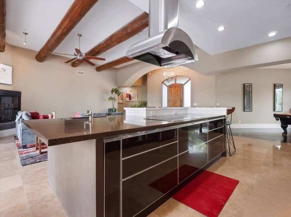Your gourmet kitchen features gleaming countertops, a chef's hood, and exposed wooden beams that blend rustic charm with modern elegance—perfect for creating memorable meals.