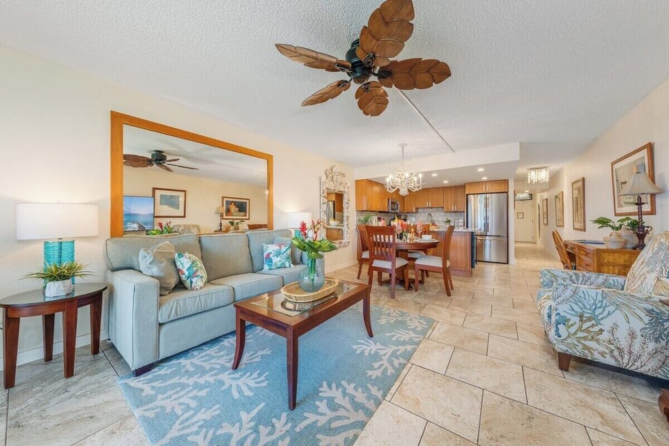 Stylish open-plan space features a cozy sofa, tropical ceiling fan, and seamless flow to the dining and kitchen