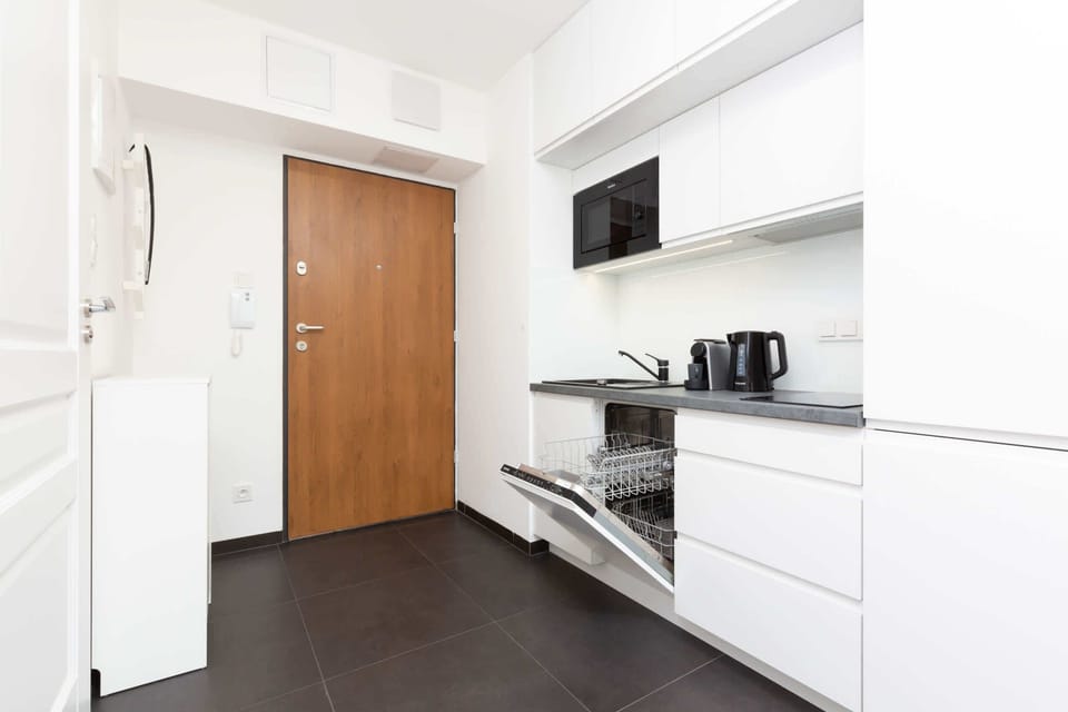 A compact yet stylish kitchen featuring high-gloss white cabinets, a built-in oven, and a neat layout.
