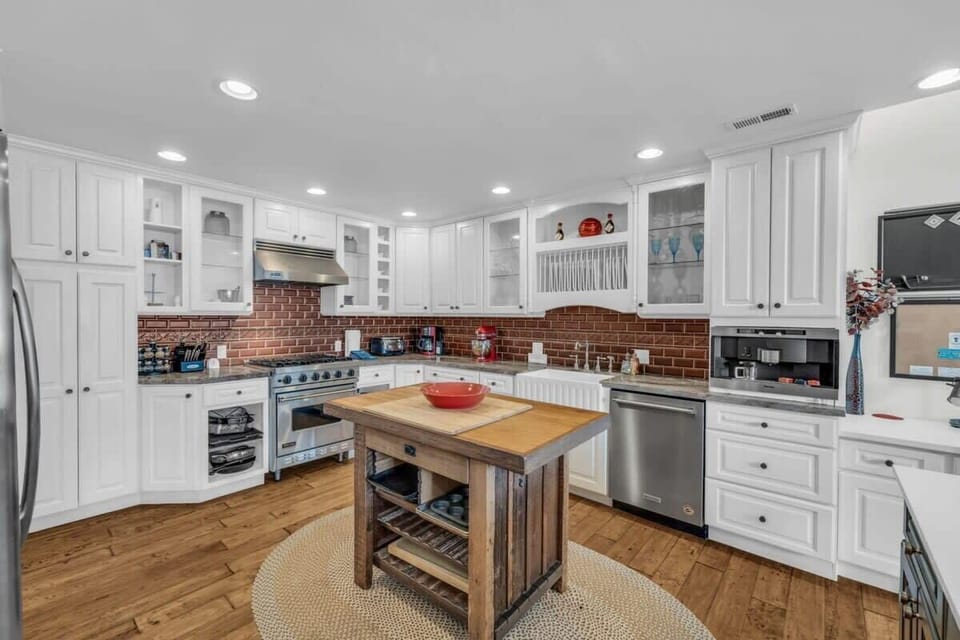 The kitchen has a rustic charm with exposed red bricks contrasting against the white cabinetry, the chef in your group will love preparing meals in this lovely space.