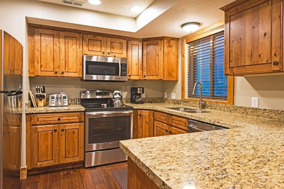 Fully-equipped kitchen with high-quality stainless steel appliances, and breakfast bar stool seating
