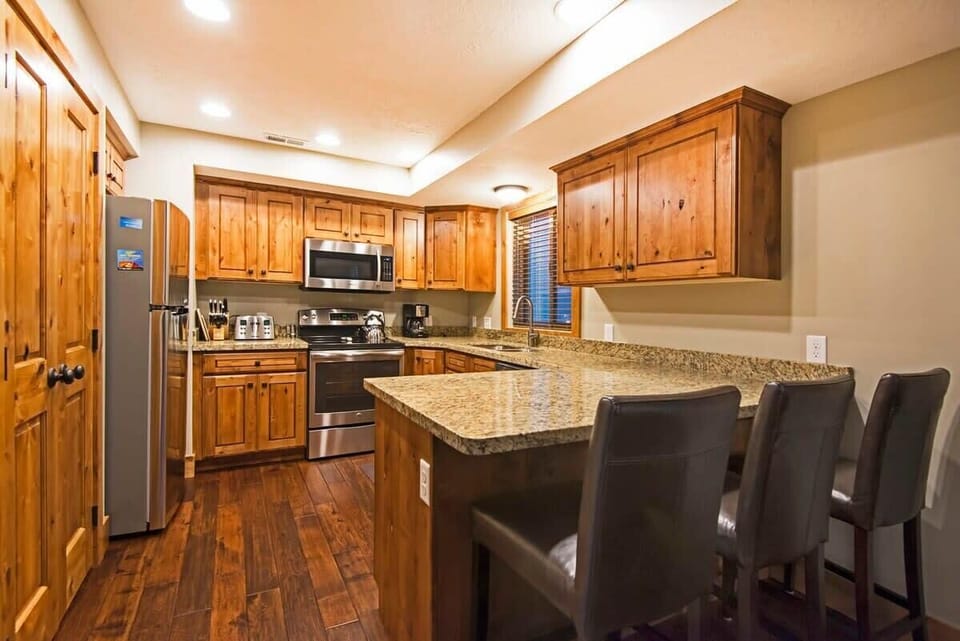 Fully-equipped kitchen with high-quality stainless steel appliances, and breakfast bar stool seating