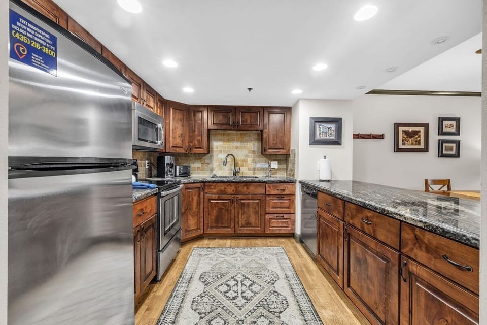 The kitchen features modern stainless steel appliances, granite countertop, and breakfast bar seating.
