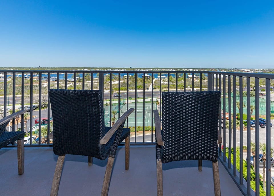 Master balcony seating offers a serene view of the marina and tennis courts, perfect for relaxing in the sun