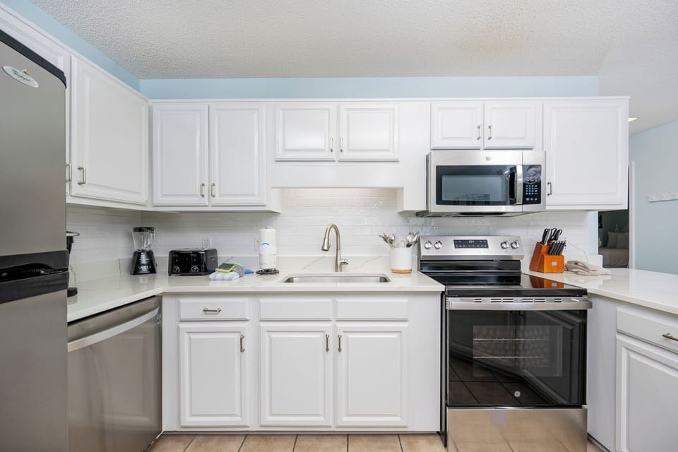 Bright white cabinetry and sleek countertops complement a modern kitchen with stainless appliances and a cozy atmosphere
