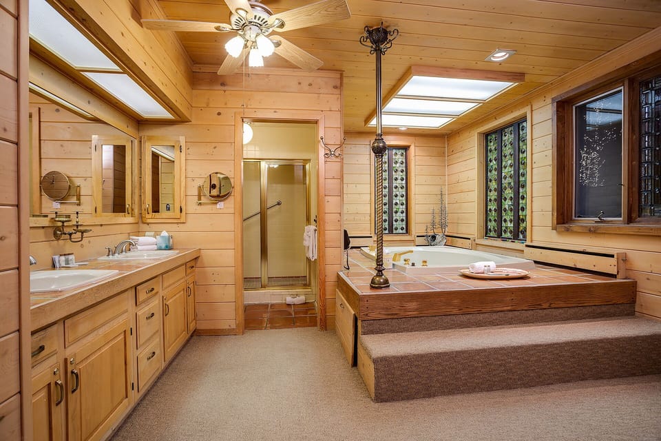 Unwind in your spacious en suite bath, where warm wood tones, skylight glow, and a luxurious sunken tub invite you to relax after a day exploring nearby trails.