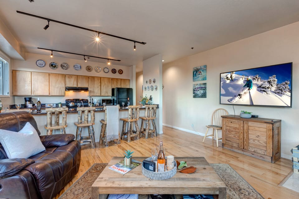 Living Room with 65" Sony Smart TV, wood-burning fireplace, plush leather furnishings, and private balcony access overlooking Park Ave.