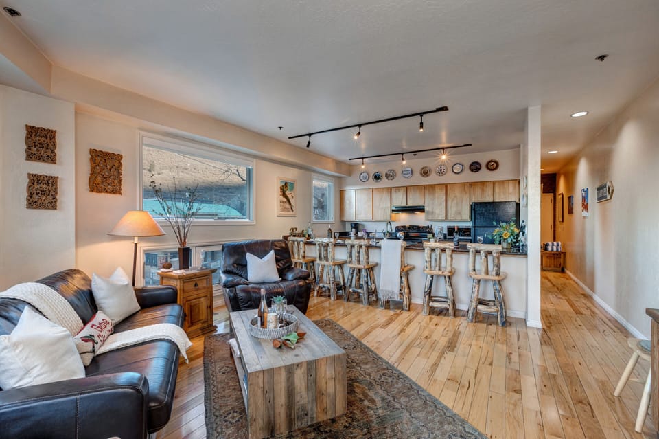 Living Room with 65" Sony Smart TV, wood-burning fireplace, plush leather furnishings, and private balcony access overlooking Park Ave.
