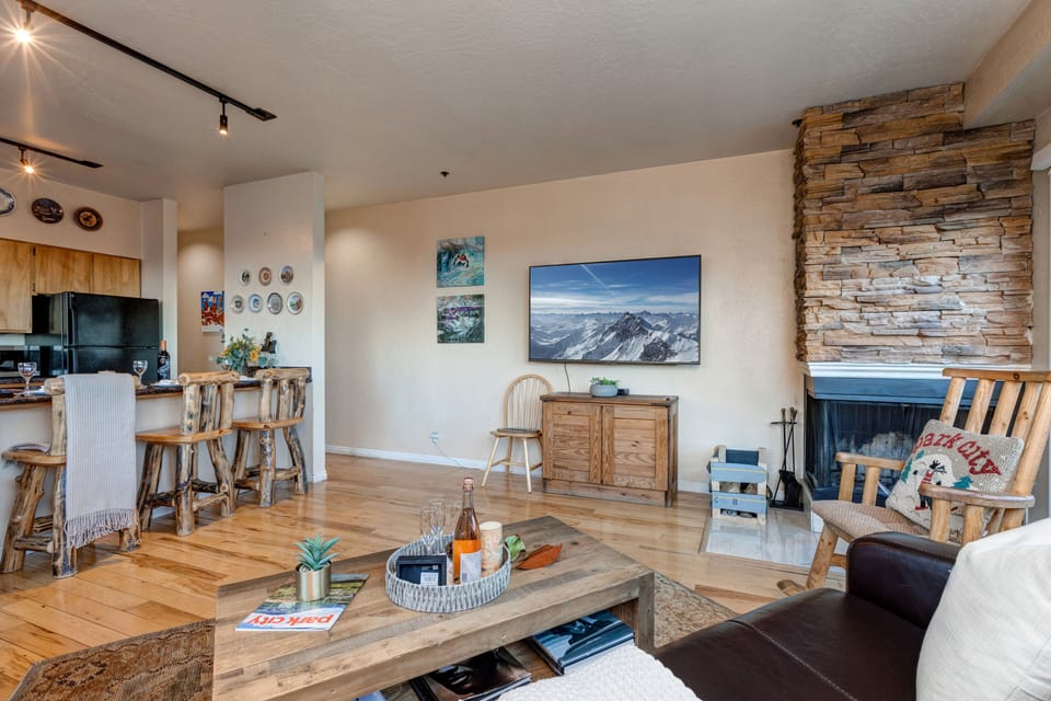 Living Room with 65" Sony Smart TV, wood-burning fireplace, plush leather furnishings, and private balcony access overlooking Park Ave.