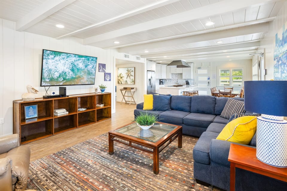 Relax in your spacious open-concept living area with plush sectional seating, entertainment center, and seamless flow to the modern kitchen.