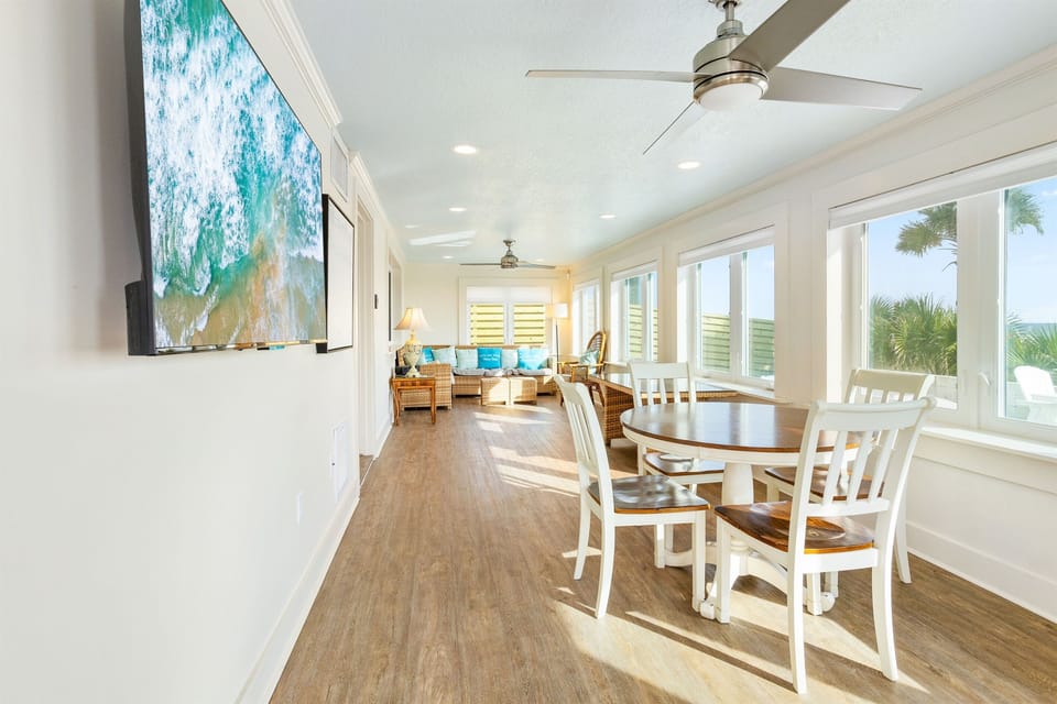Relax in your bright open-plan living space with ocean-inspired art, comfortable seating, and stunning tropical views through panoramic windows.