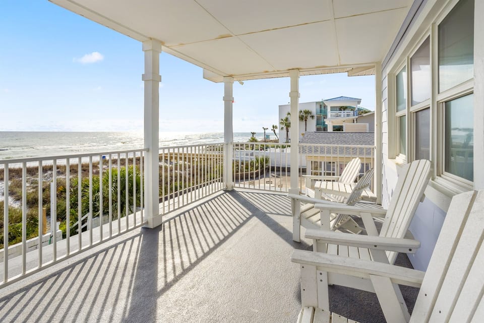 Expansive balcony overlooking Gulf waters with white Adirondack chairs perfectly positioned for sunset views and ocean breezes.