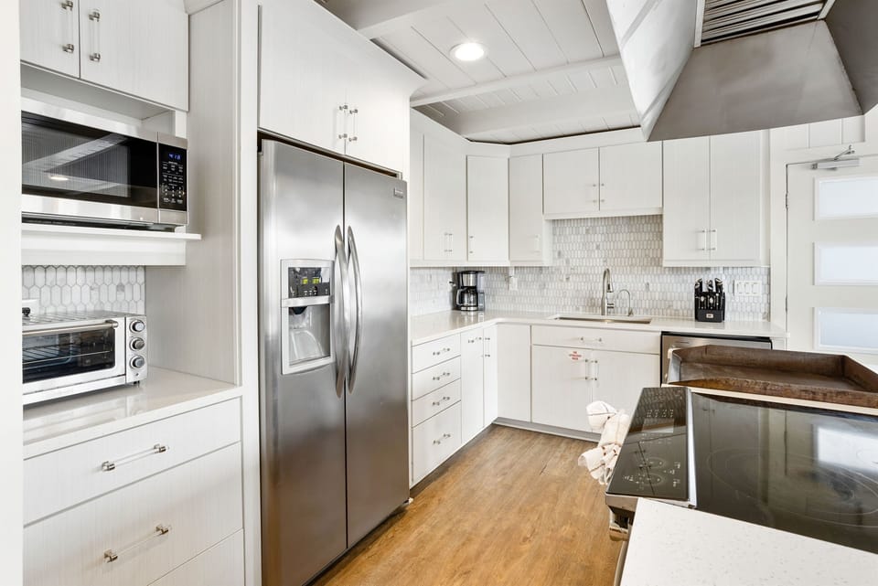 Your gourmet kitchen features sleek white cabinetry, stainless steel appliances, and elegant quartz countertops for memorable meal preparation.