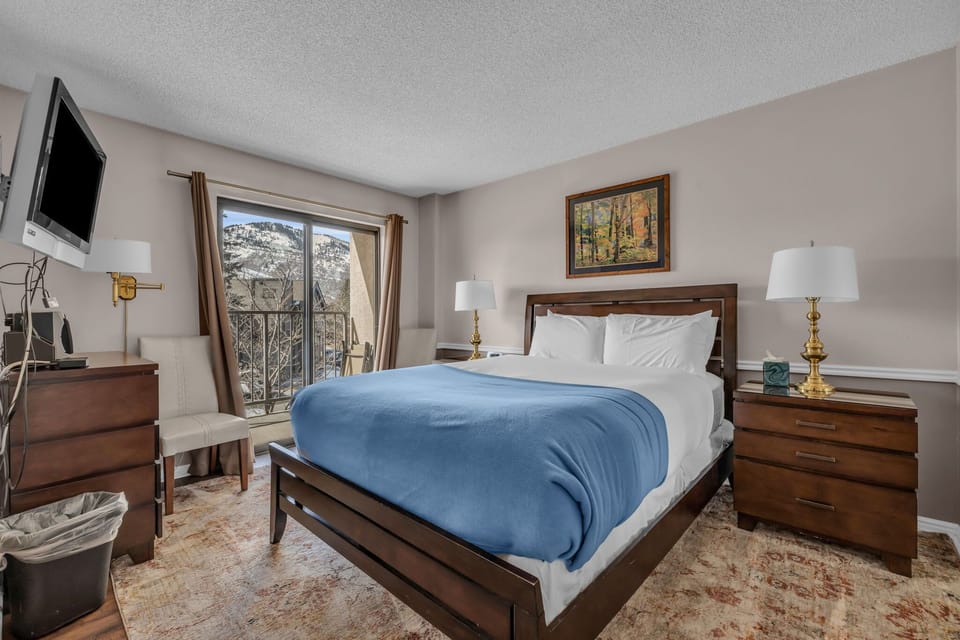 Main bedroom with a lovely queen-size bed, a full-length mirror, ample closet space, a flat-screen TV, access to the private outdoor balcony, and an en suite bathroom