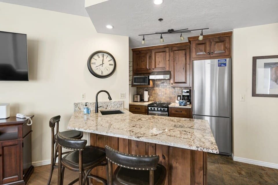 The modern, fully-equipped kitchen features stainless steel appliances, and bar seating for 3.