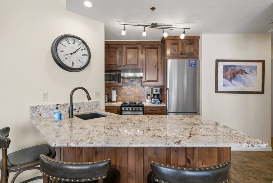 The modern, fully-equipped kitchen features stainless steel appliances, and bar seating for 3.