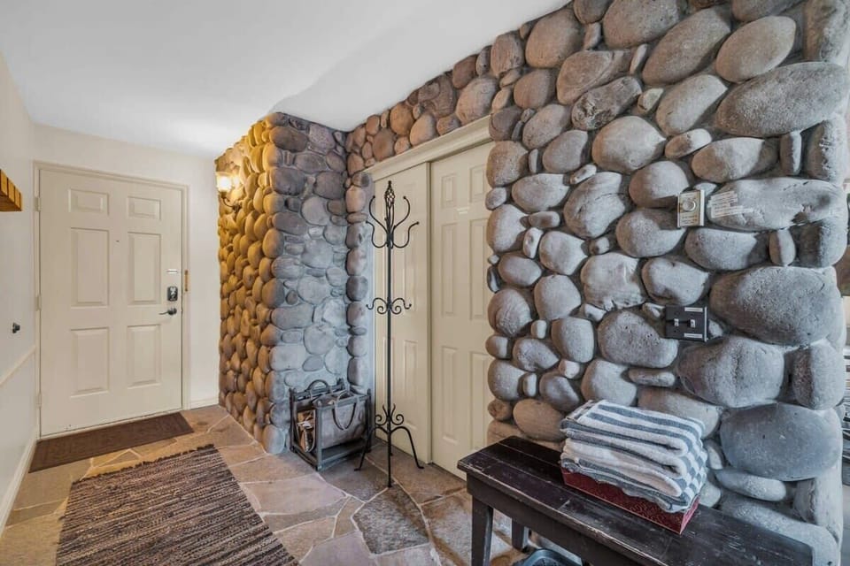 The view of the entryway of the home where a cozy living room and rock wall greet you.