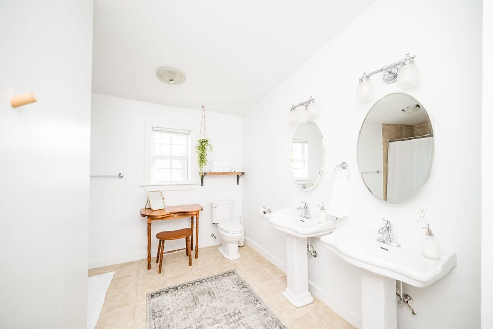 Spacious primary bathroom w/ a view of the James River, 2 sinks, & shower/tub
