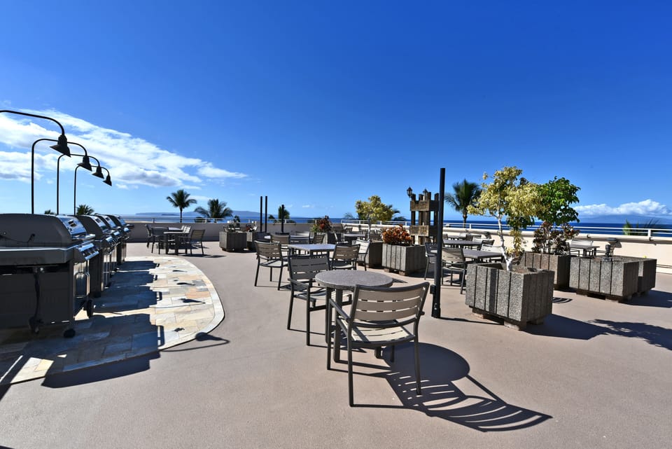Rooftop outdoor dining with table, chairs, BBQs, and kitchenette.