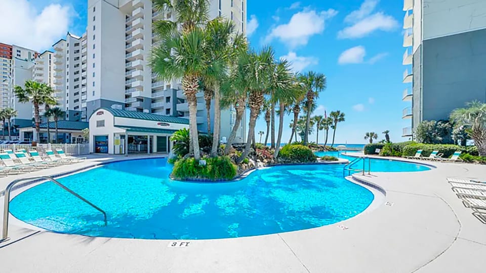 Oversized lagoon pool that is directly overlooking the beach with lush palms and waterfall islands.