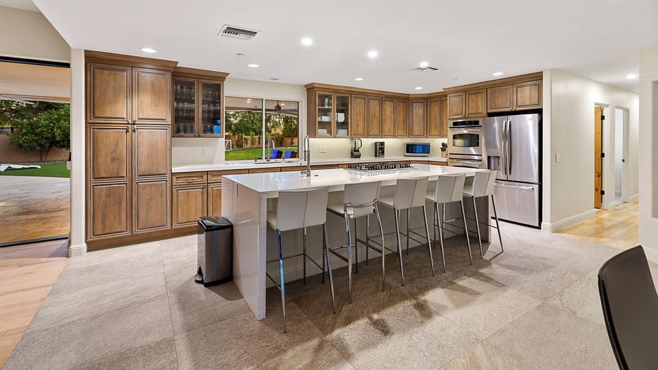 Gourmet kitchen with quartz island, stainless appliances, and backyard access