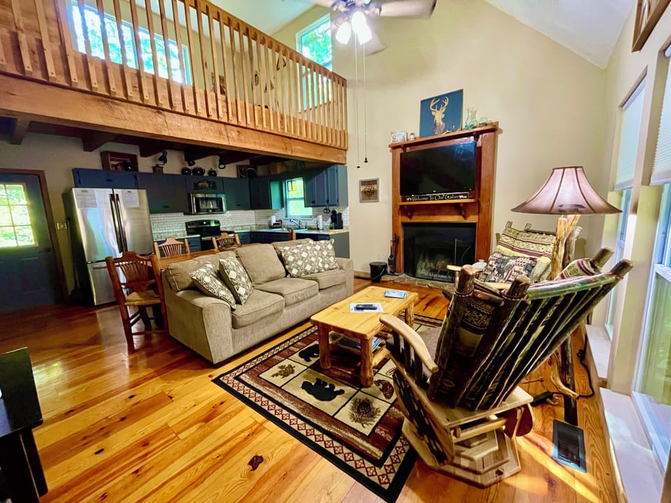 Comfortable great room with a wood burning fireplace, 2 rockers, a sofa open to the kitchen