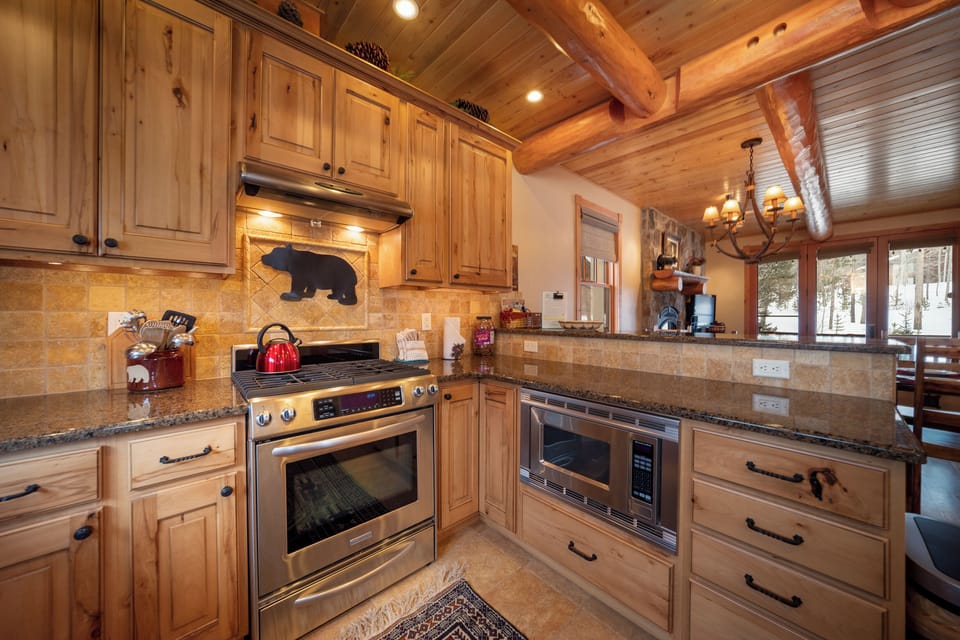 Step into your mountain retreat's fully equipped kitchen, where rustic wood cabinets and granite counters create the perfect space for preparing meals together.