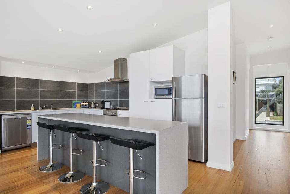 Kitchen with island bench, brekky bar, dishwasher, electric oven, microwave, fridge and coffee pod machine