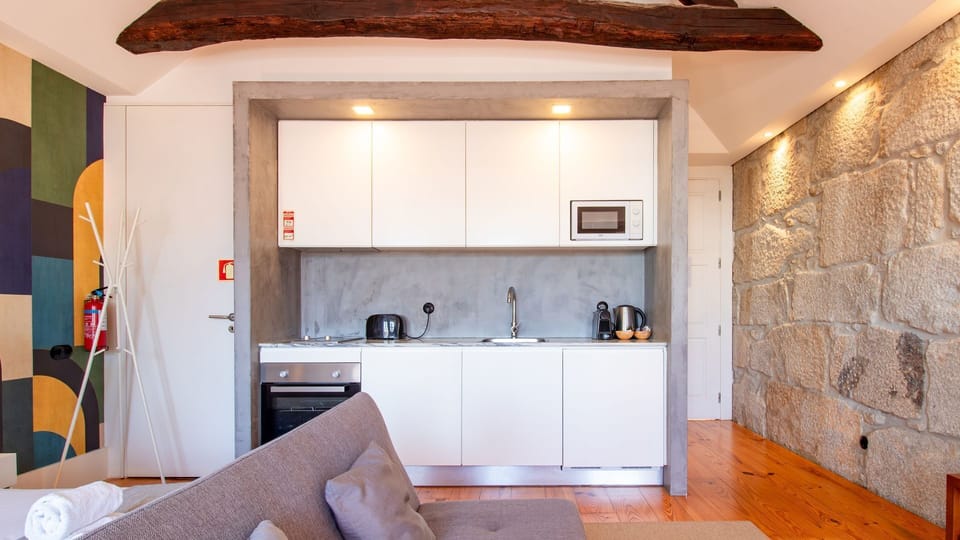 Imagine whipping up a quick meal in your compact, stylish kitchenette, then relaxing on the comfortable sofa, all while enjoying the rustic charm of the exposed stone wall and historic wooden beams. This cozy studio offers modern convenience nestled withi