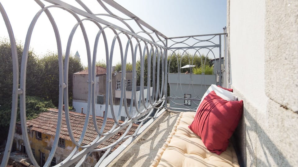Unwind on the charming balcony, enjoying unique cityscape views over the rooftops of Porto, perfect for a quiet morning coffee or an evening drink. The ornate railing adds a touch of classic elegance to your private outdoor escape.