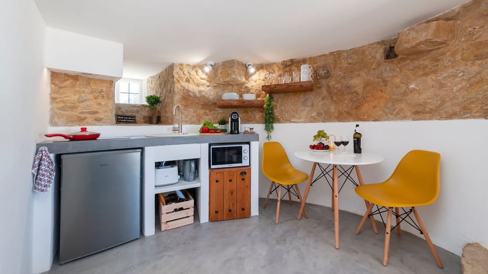 Enjoy simple home-cooked meals in the stylish kitchenette, blending modern comfort with traditional stone walls. #Kitchenette #RusticCharm #HomeAwayFromHome #TinyKitchen #Portugal #PT #SobralDaAbelheira #Mafra