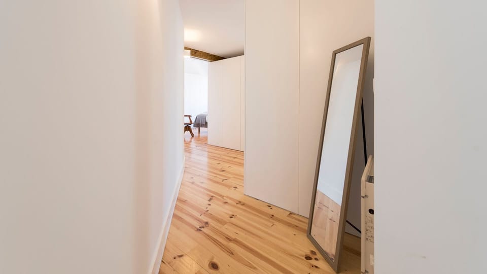 Walk through this bright, modern corridor connecting to your cozy sleeping spaces, stopping to check your reflection in the full-length mirror. The gleaming wooden floors add warmth and elegance to your passage.